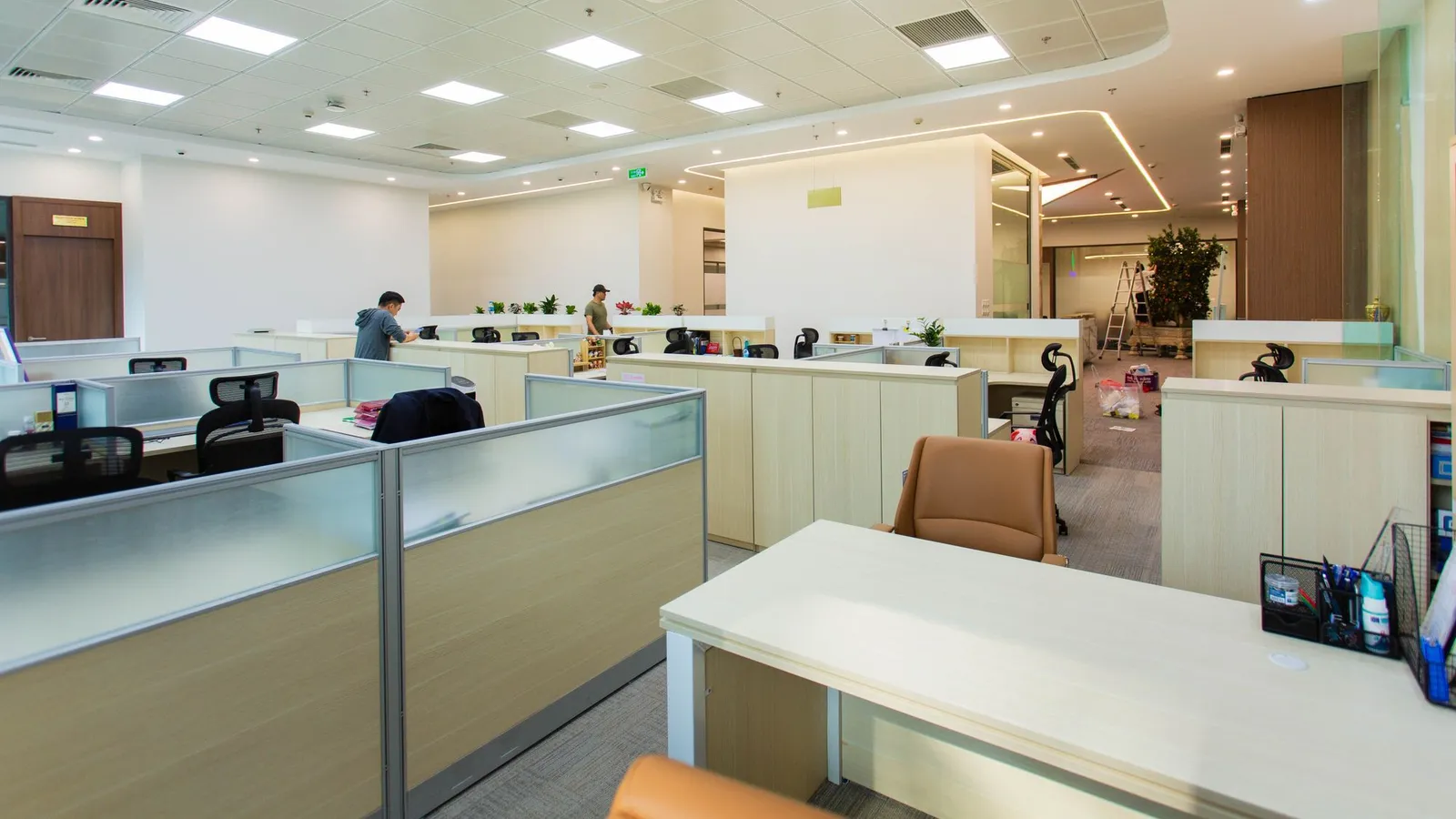 Open-plan office with frosted-glass desk screens, recessed ceiling panels and rows of workstations