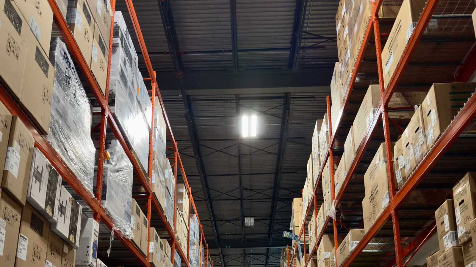 Tall orange pallet racking loaded with boxes along a warehouse aisle