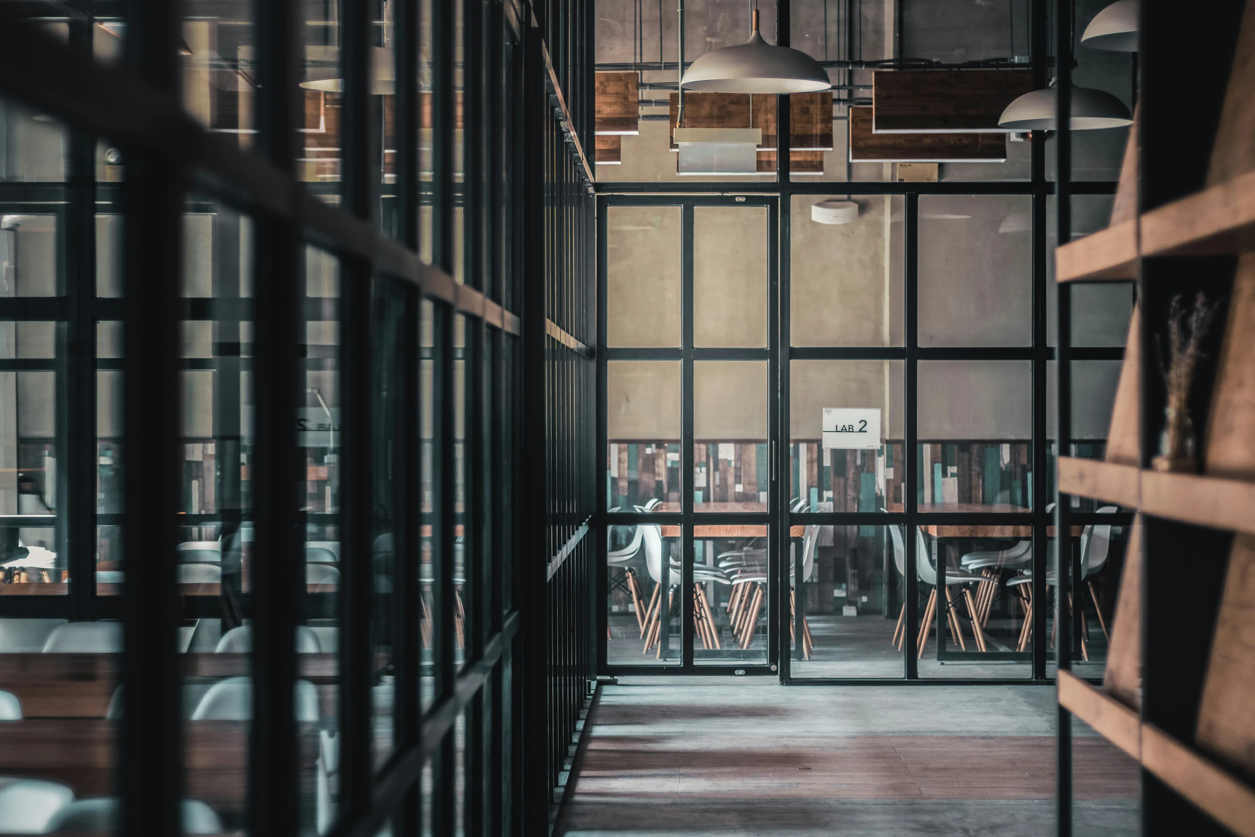 Glass-walled office corridor leading to a meeting space, reflecting modern commercial interior design