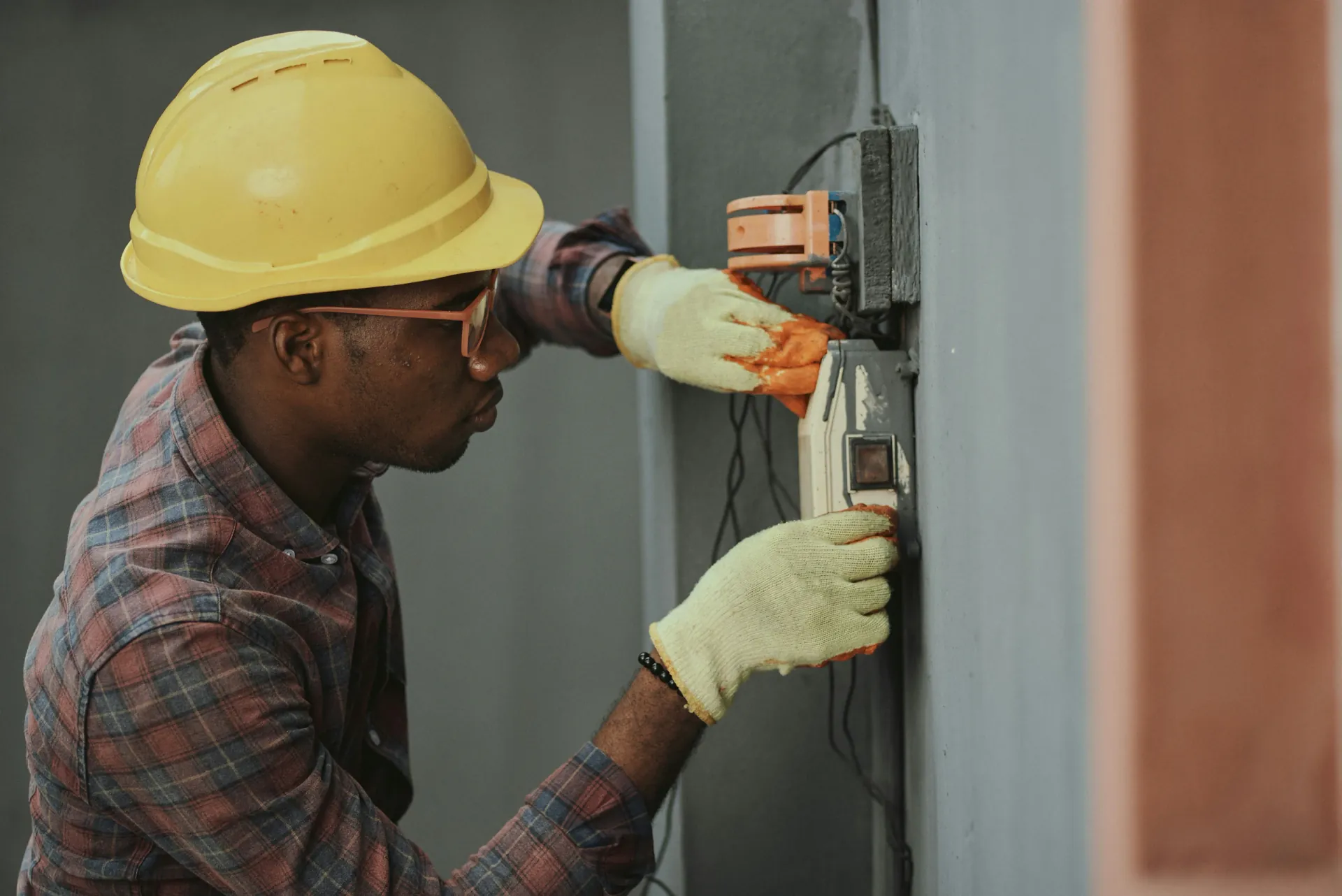 Electrician in a hard hat installing a junction box and wiring during a fit-out