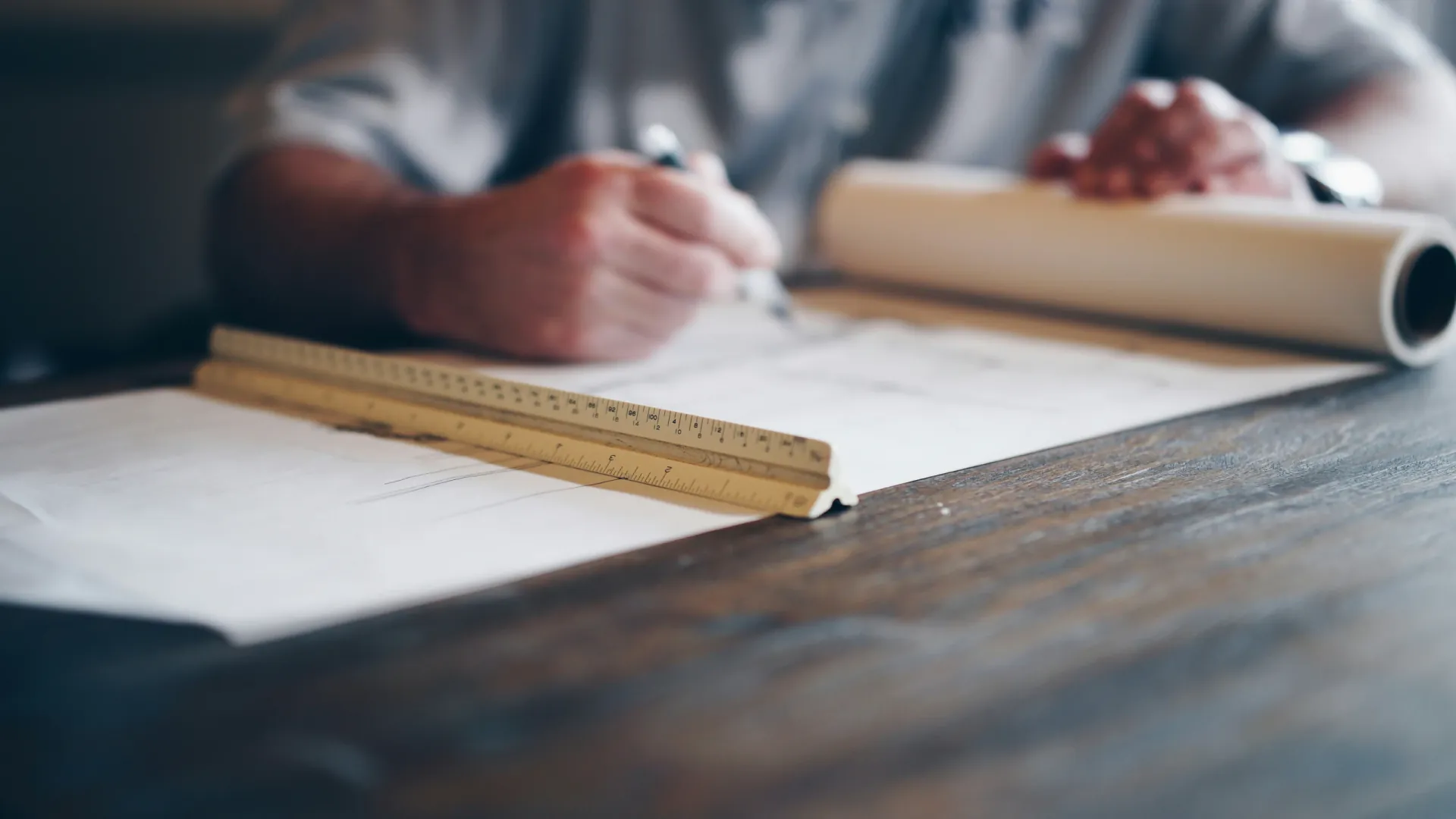 Close-up of hands drafting a technical structural drawing with a ruler