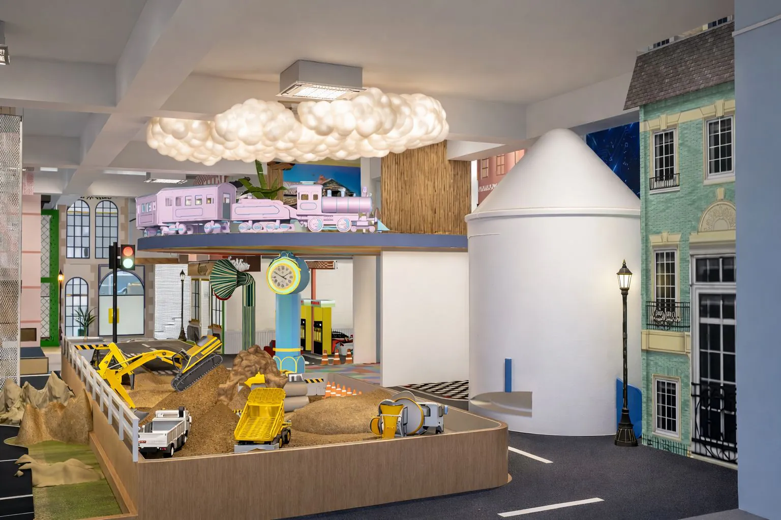 Indoor sand play area with toy diggers and dumper trucks beside a play street