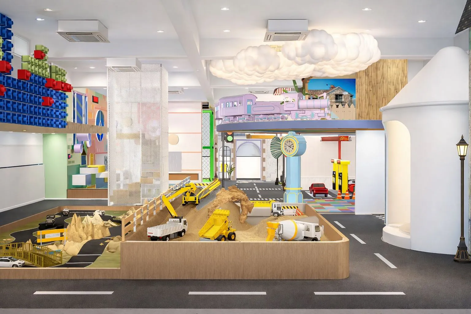 Raised landscape play table with toy vehicles beside a wall of coloured ball storage
