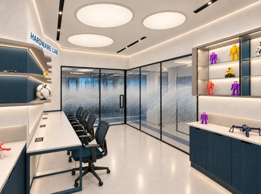 Hardware lab with a long white workbench, mesh chairs, lit display shelves of robots and a glazed partition with dot-gradient film
