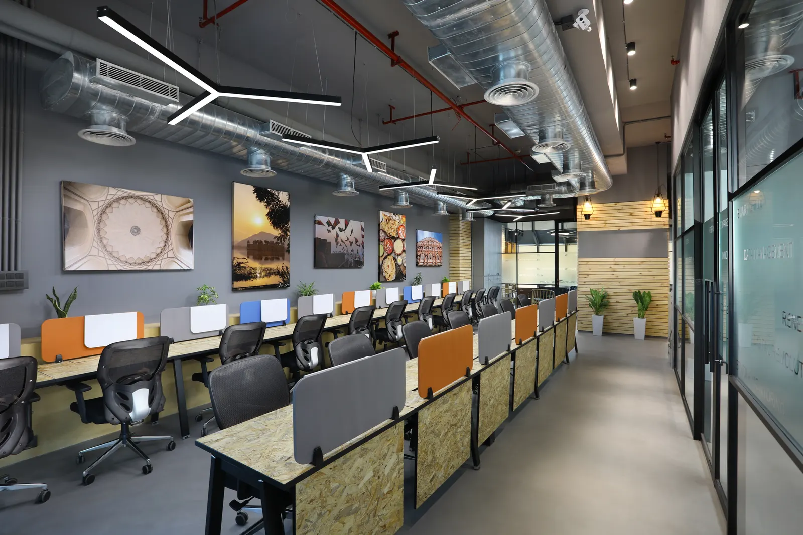 EDF International open-plan office with orange-accented workstation screens under an exposed services ceiling