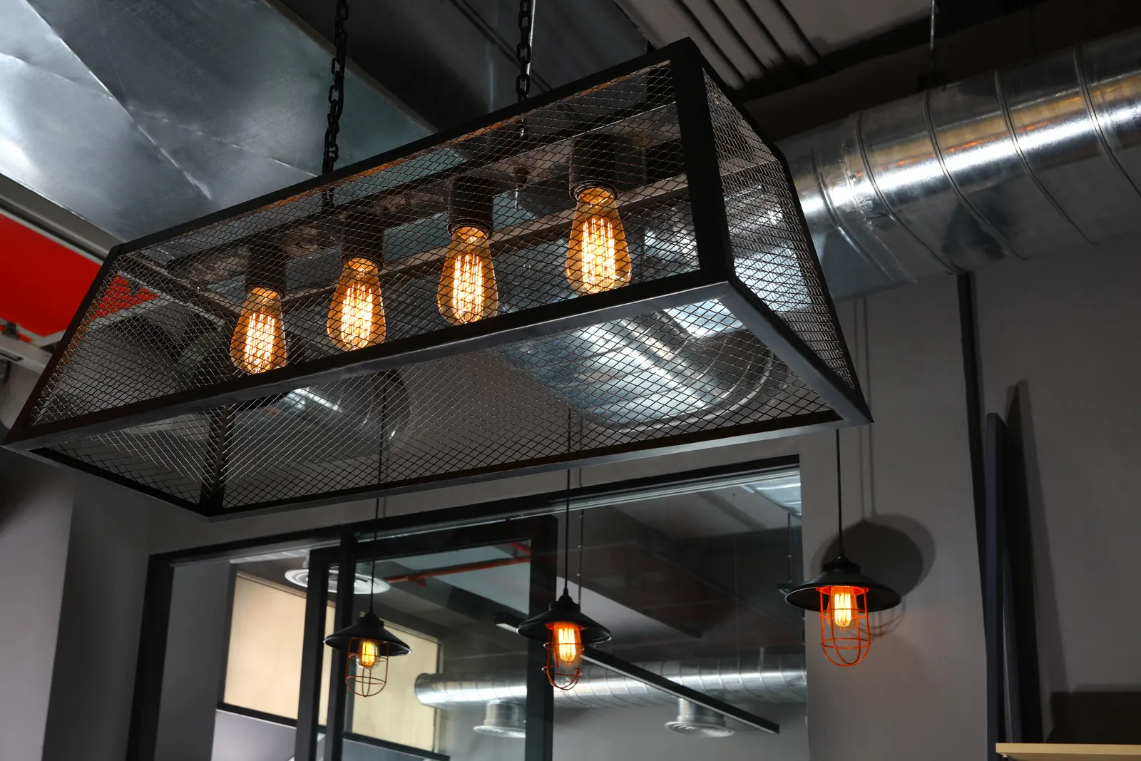 Black cage pendant light with exposed filament bulbs over the EDF International office entrance