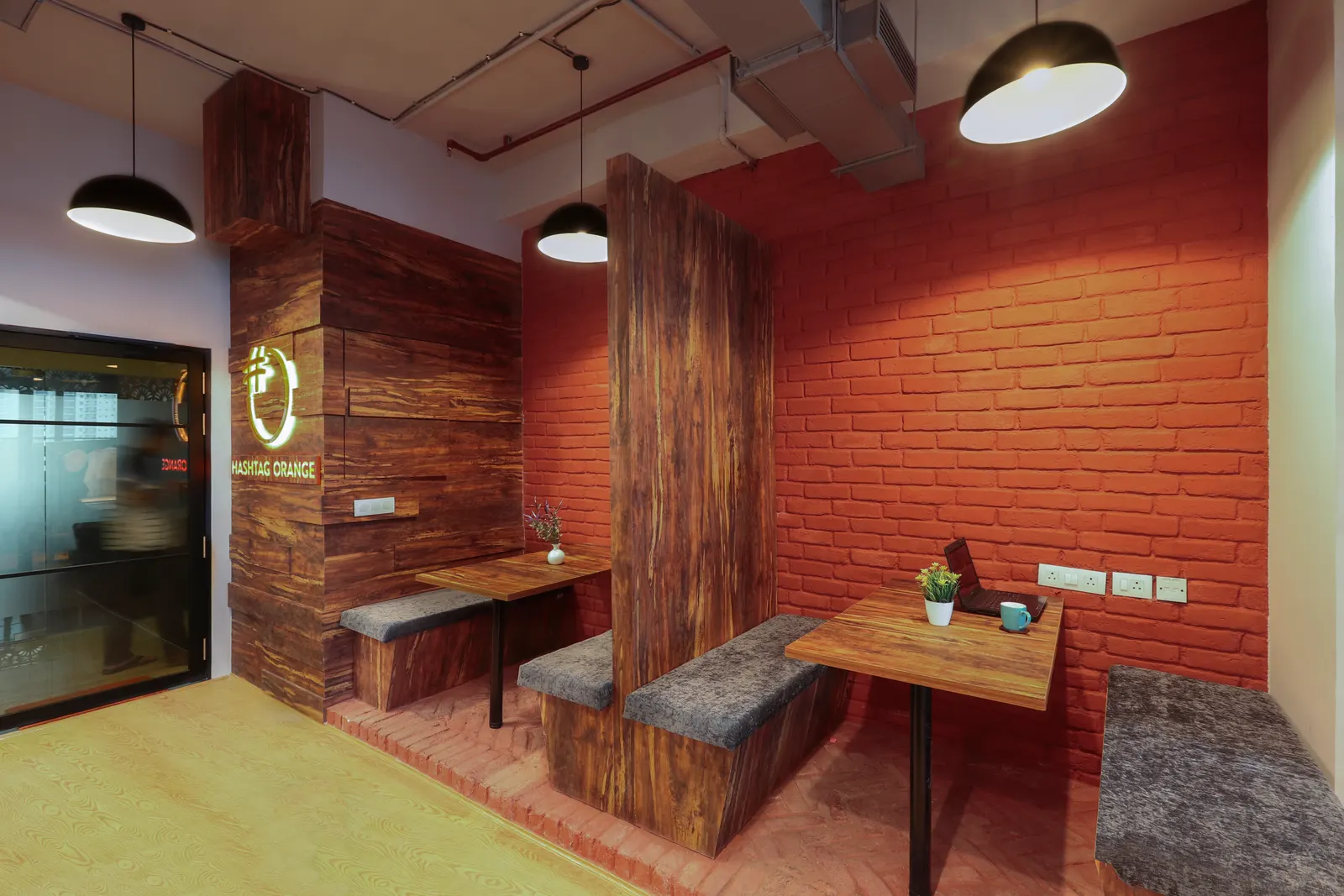 Hashtag Orange booth seating against a red exposed-brick wall with timber tables