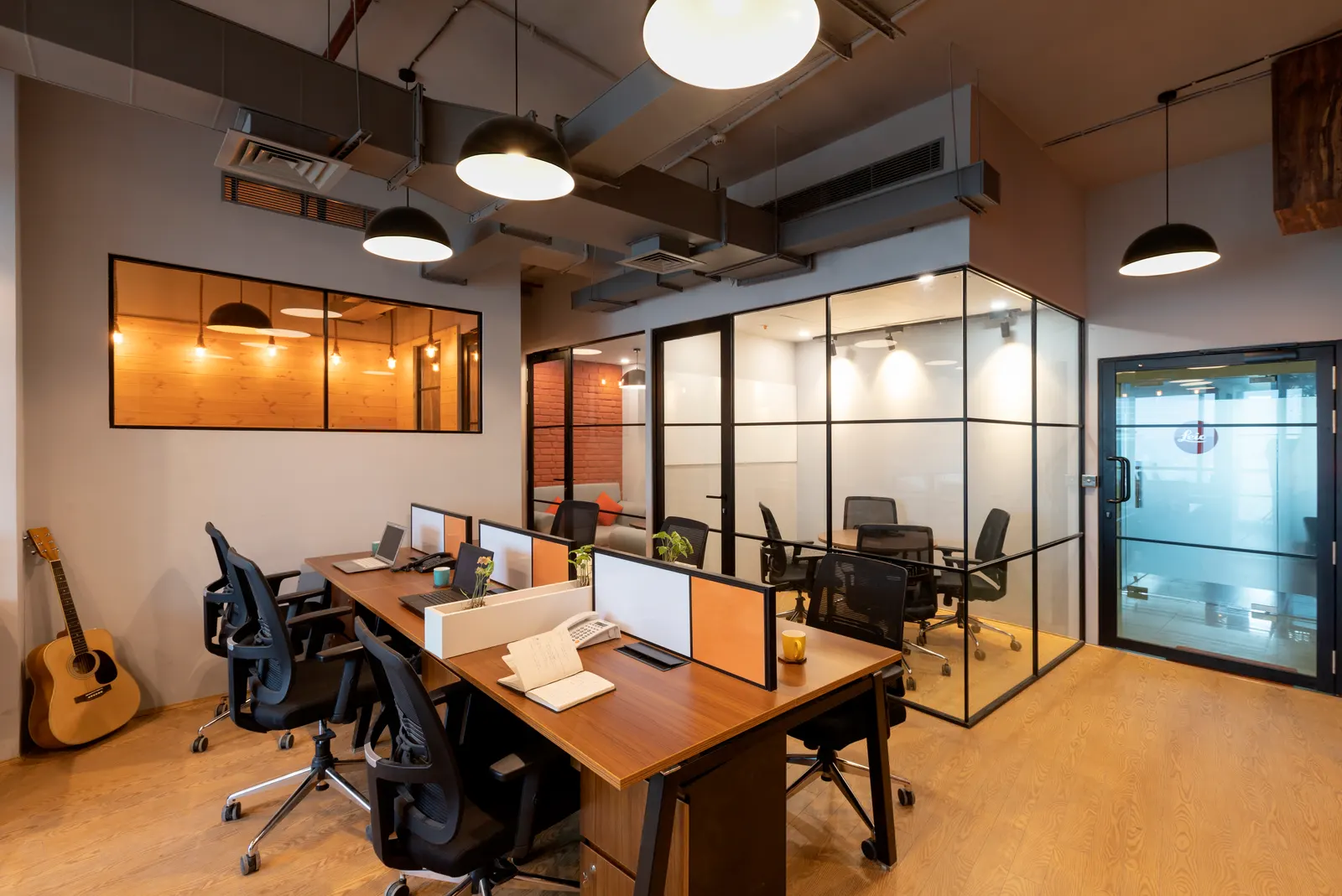 Hashtag Orange glass and black-framed cabins beside the open workstation area