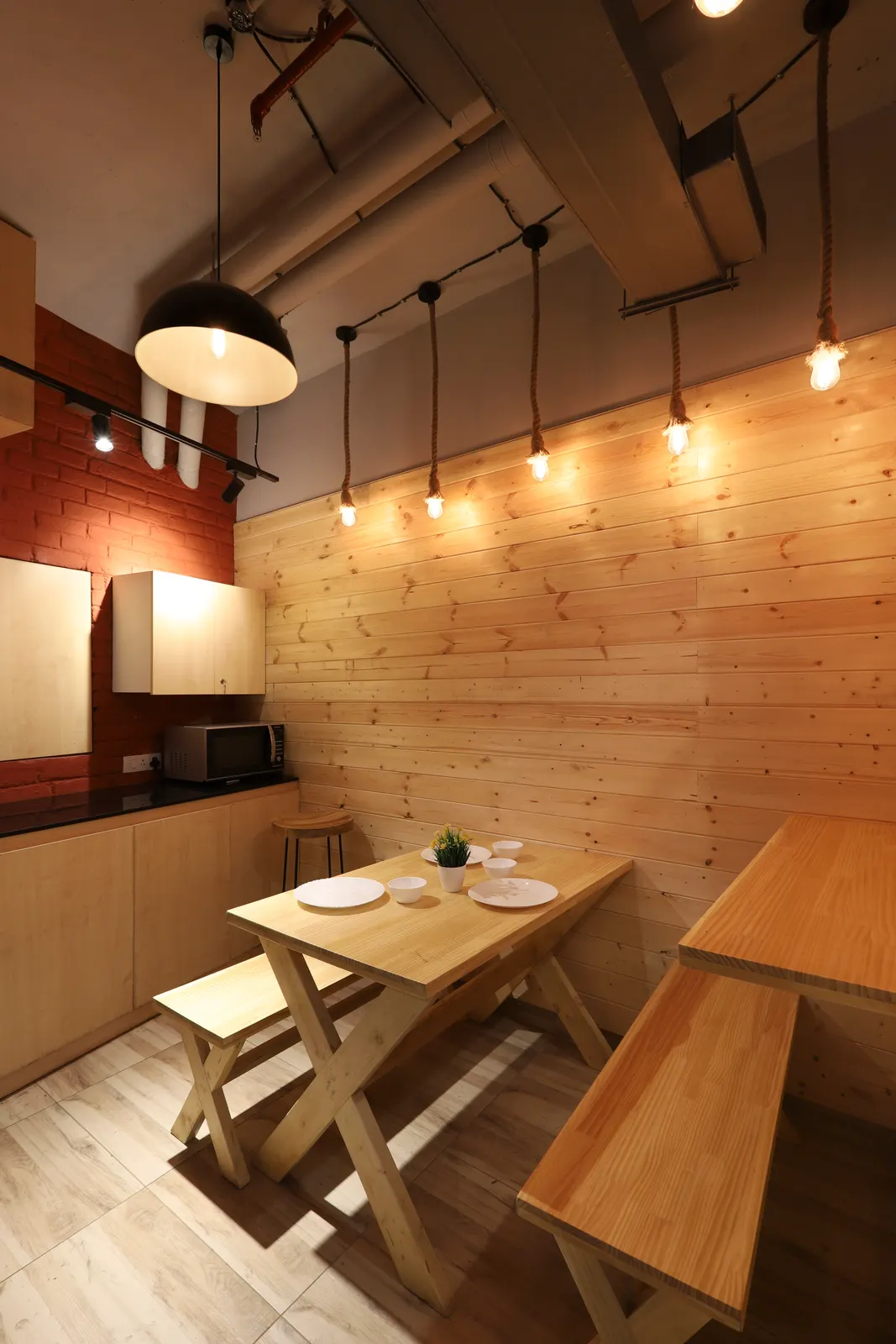 Hashtag Orange pantry with pine-clad walls, filament pendant lights and a timber dining table
