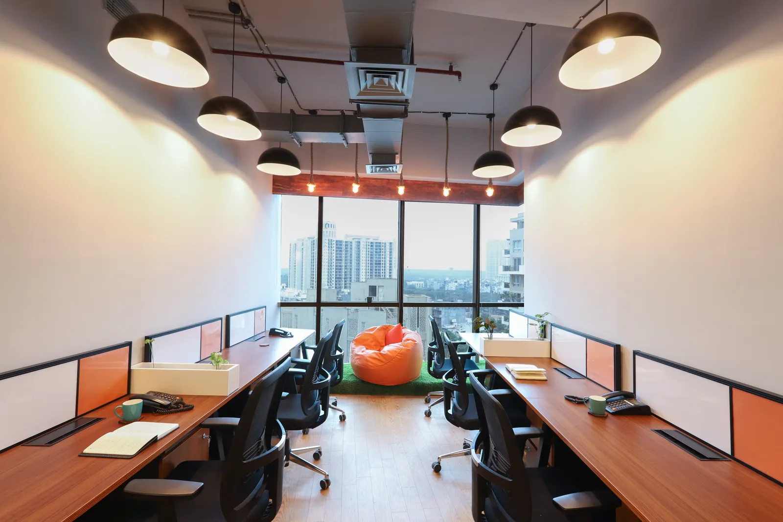 Hashtag Orange office workstations running to full-height windows with a city view