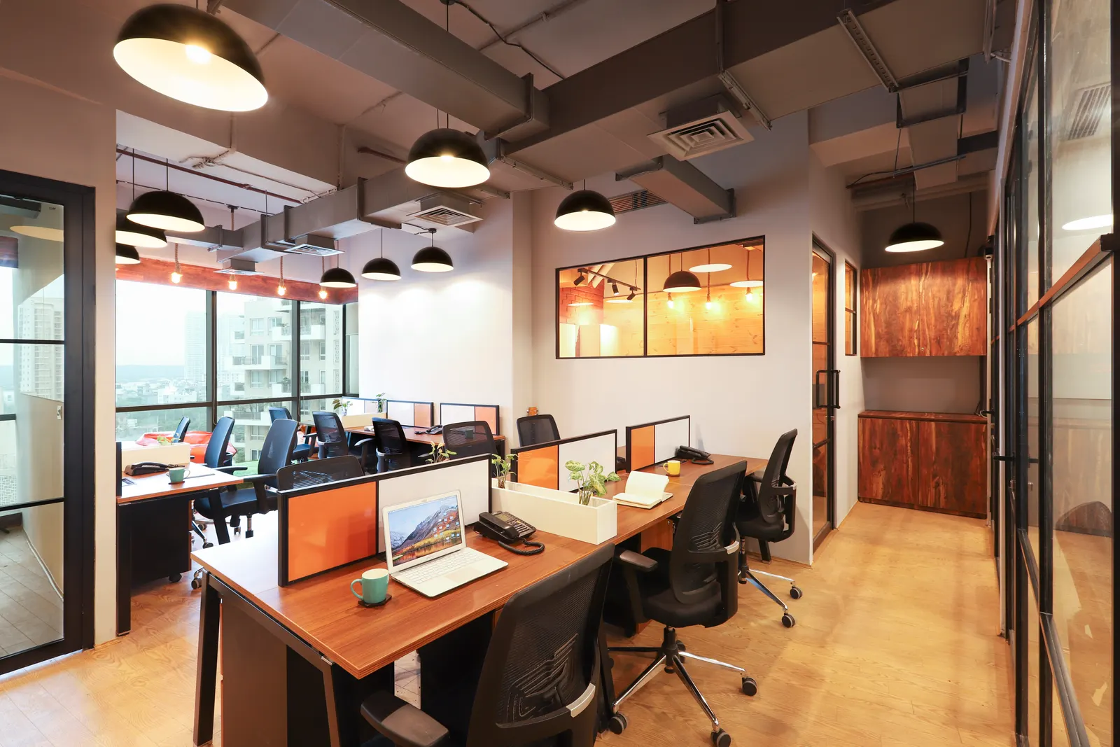 Hashtag Orange workstations with orange and white screens under an exposed ceiling