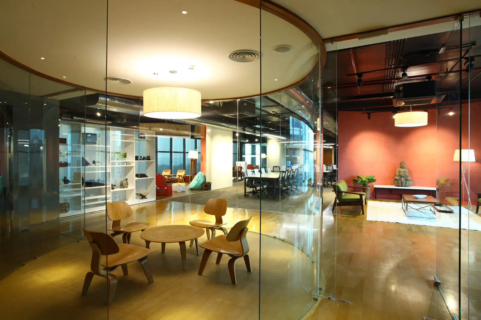 Inshorts Media curved glass meeting area with timber chairs and round tables