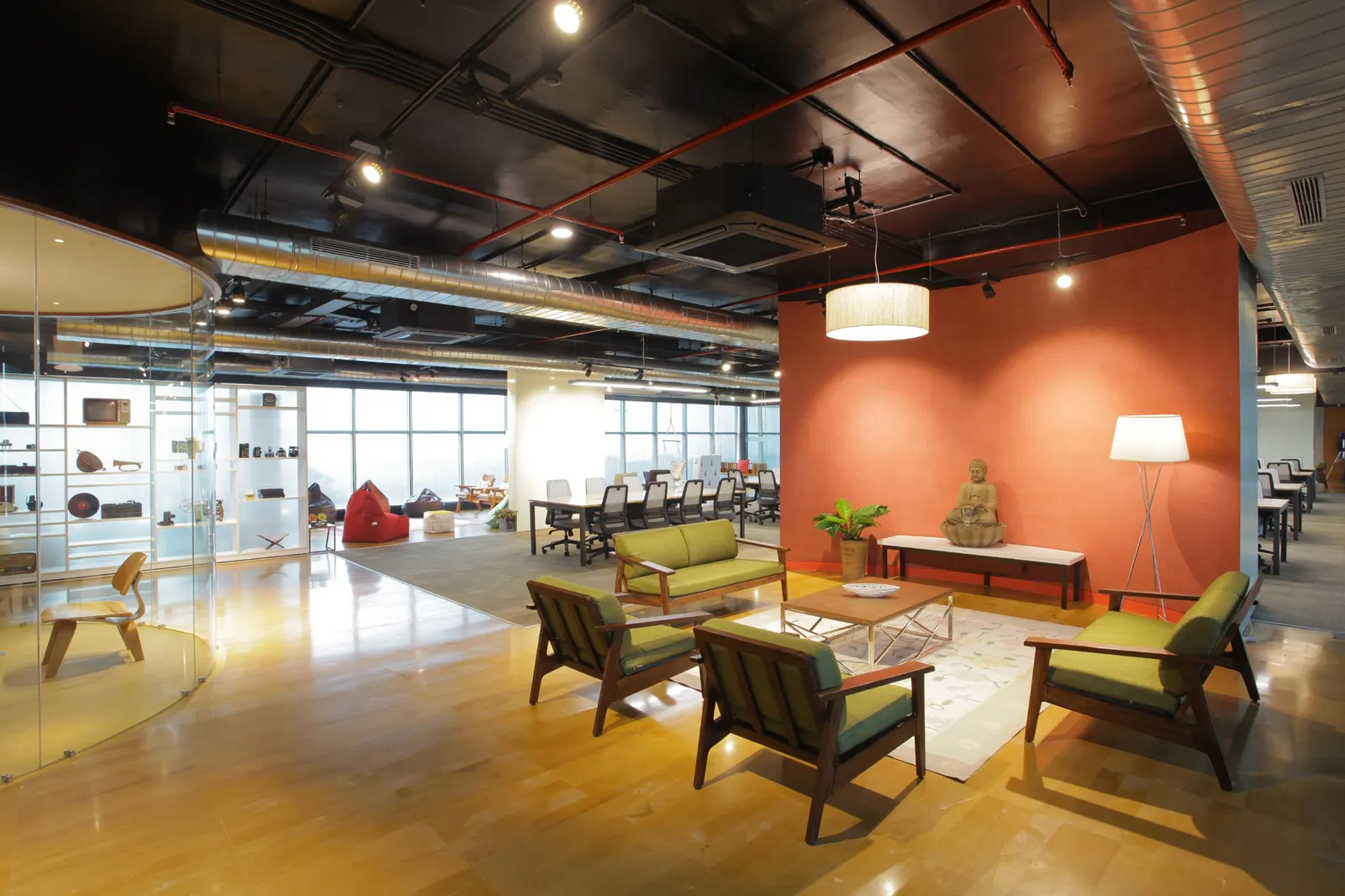 Inshorts Media office lounge in Noida with armchairs, a terracotta feature wall and an exposed black ceiling