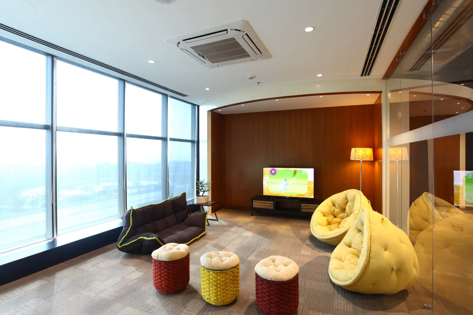 Inshorts Media recreation room with yellow bean chairs, poufs and a TV wall