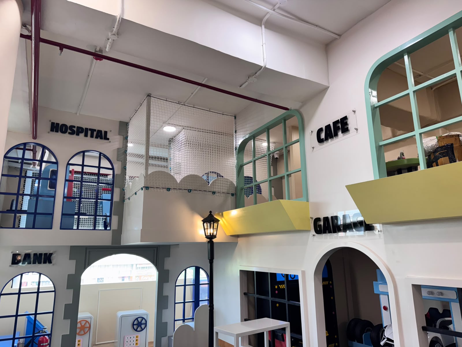 Wide view of the Kokko Town pretend-play town with Hospital, Bank, Cafe and Garage facades across two levels