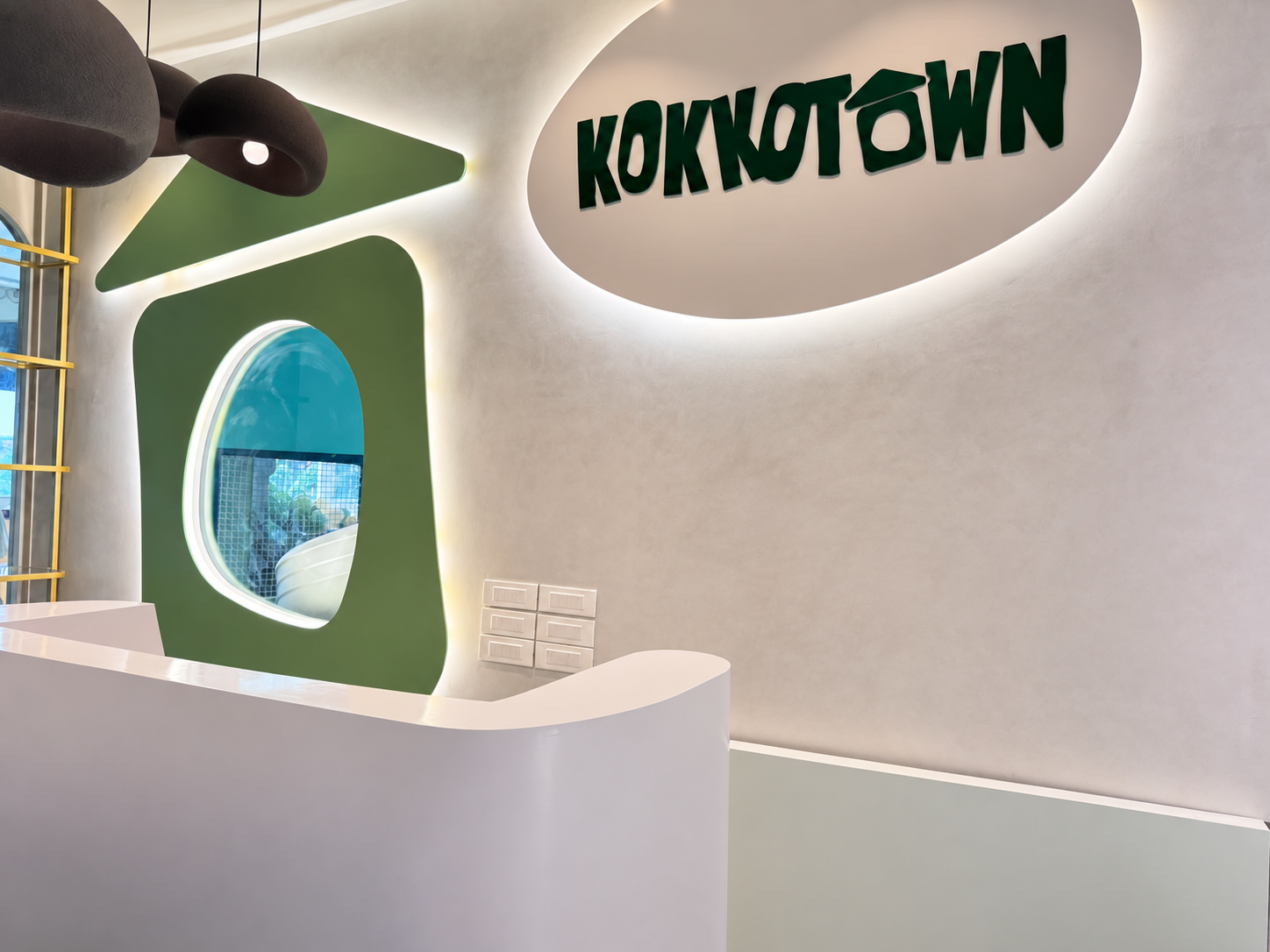 Kokko Town reception desk with a green airplane-window feature wall and backlit signage in Sector 17, Chandigarh