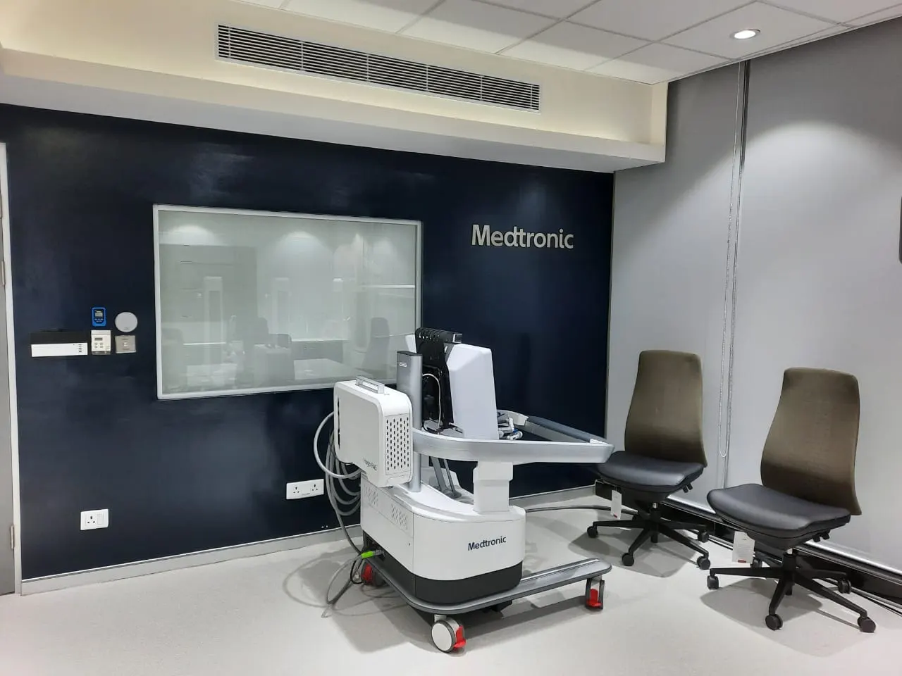Medtronic demo room in Gurugram with a navy feature wall, glazed viewing panel and medical equipment