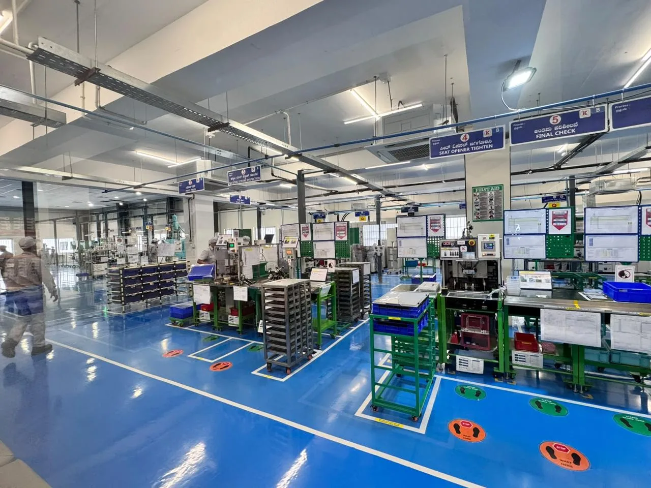 MinebeaMitsumi production floor in Peenya, Bengaluru with epoxy-coated blue flooring, overhead cable trays and assembly workstations