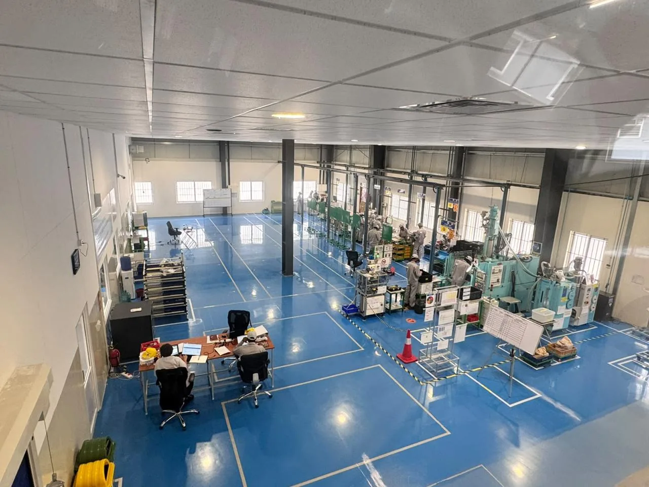 Mezzanine-level overview of the MinebeaMitsumi shop floor with injection moulding machines and workstations