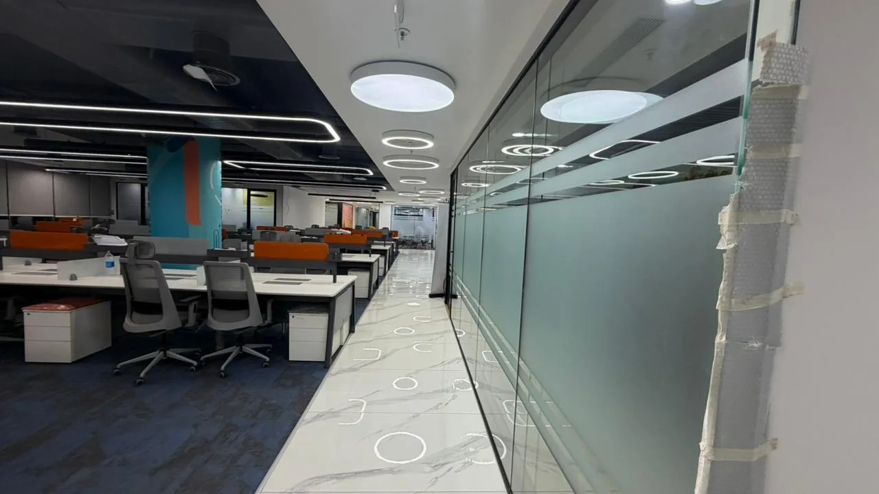 Glazed corridor with frosted glass partitions and marble flooring at the SAEL office
