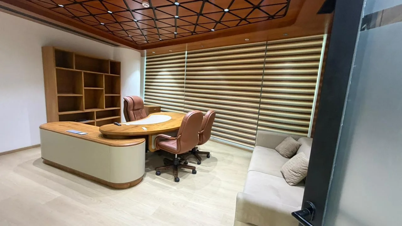 SAEL MD cabin with a geometric wood-lattice ceiling, curved executive desk and leather chairs