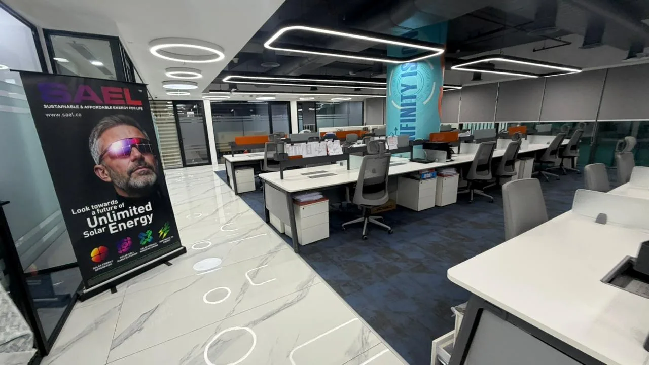 SAEL open-plan office workstations with orange dividers, blue carpet and marble walkway in Aerocity, Delhi