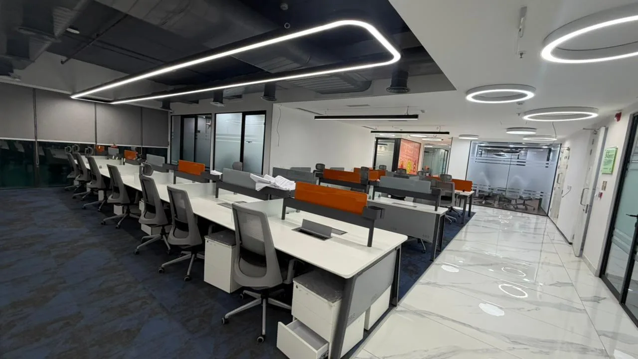 Row of SAEL office workstations with linear ceiling lighting and marble flooring