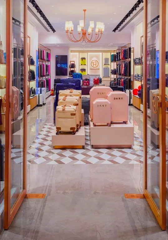 Trunkhouse luggage display on white plinths beside rose-gold shelving