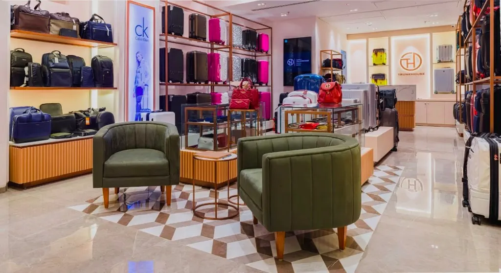 Trunkhouse luggage store in Mumbai with rose-gold shelving, green armchairs and patterned flooring