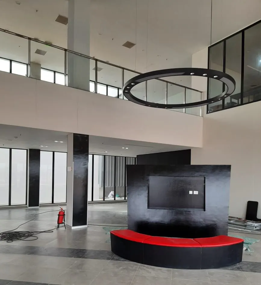 Yanmar factory double-height lobby with a ring pendant, black feature wall and curved red bench